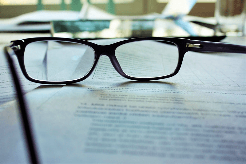 A pair of glasses on a note paper: Current Vs. Updated Specifications: DAT Biology Test 2022